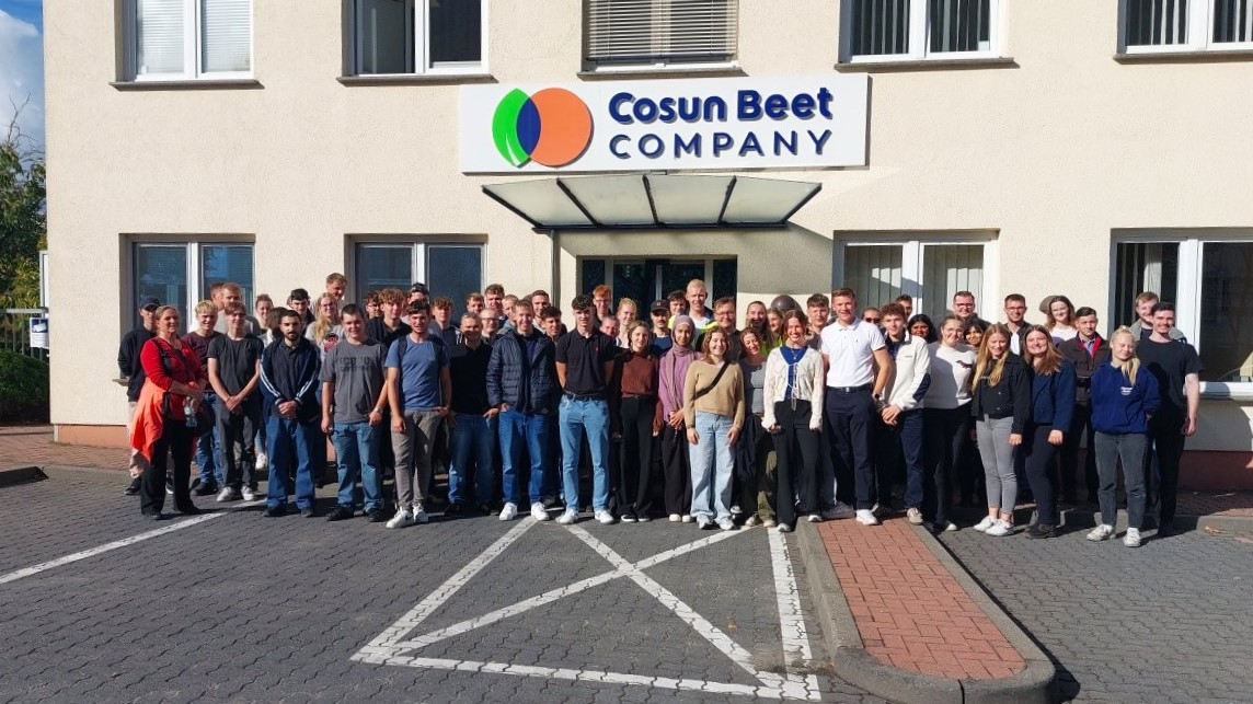 Eine große Gruppe Studierender steht, zum Gruppenfoto aufgereiht, vor dem Unternehmensgebäude der Cosun Beet Company. Über der Tür prangt das Logo in großen Lettern.