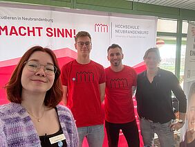 Das Foto zeigt im Selfie-Stil, von links nach rechts, Josephine Rose, Dominic Kluck, Tom Gehlhar und Juliane Häntze am Messestand im Gymnasium Grimmen. 