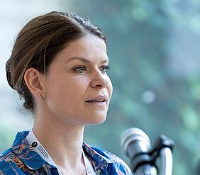 Das Foto zeigt eine Seitenansicht von Christine Krüger, Professorin an der Hochschule Neubrandenburg. Sie spricht in ein Mikrofon, der Hintergrund ist unscharf. 