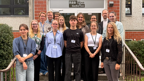 Vierzehn Personen posieren für ein förmliches Gruppenfoto auf einer Treppe am Eingang eines Hauses. Über der Eingangstür ist der Schriftzug "RBB GesoTec" zu lesen.