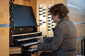 Ein Mann sitzt an einer Kirchenorgel.
