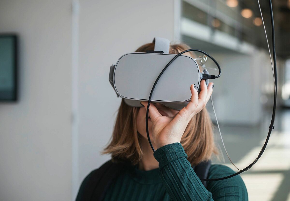 Junger Mensch hält eine VR-Brille vor die Augen