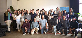 Auf diesem Gruppenfoto befinden sich alle Teilnehmenden der Tour. In drei Reihen positionieren sich die Personen und lächeln freundlich in die Kamera. Alle sind locker gekleidet.